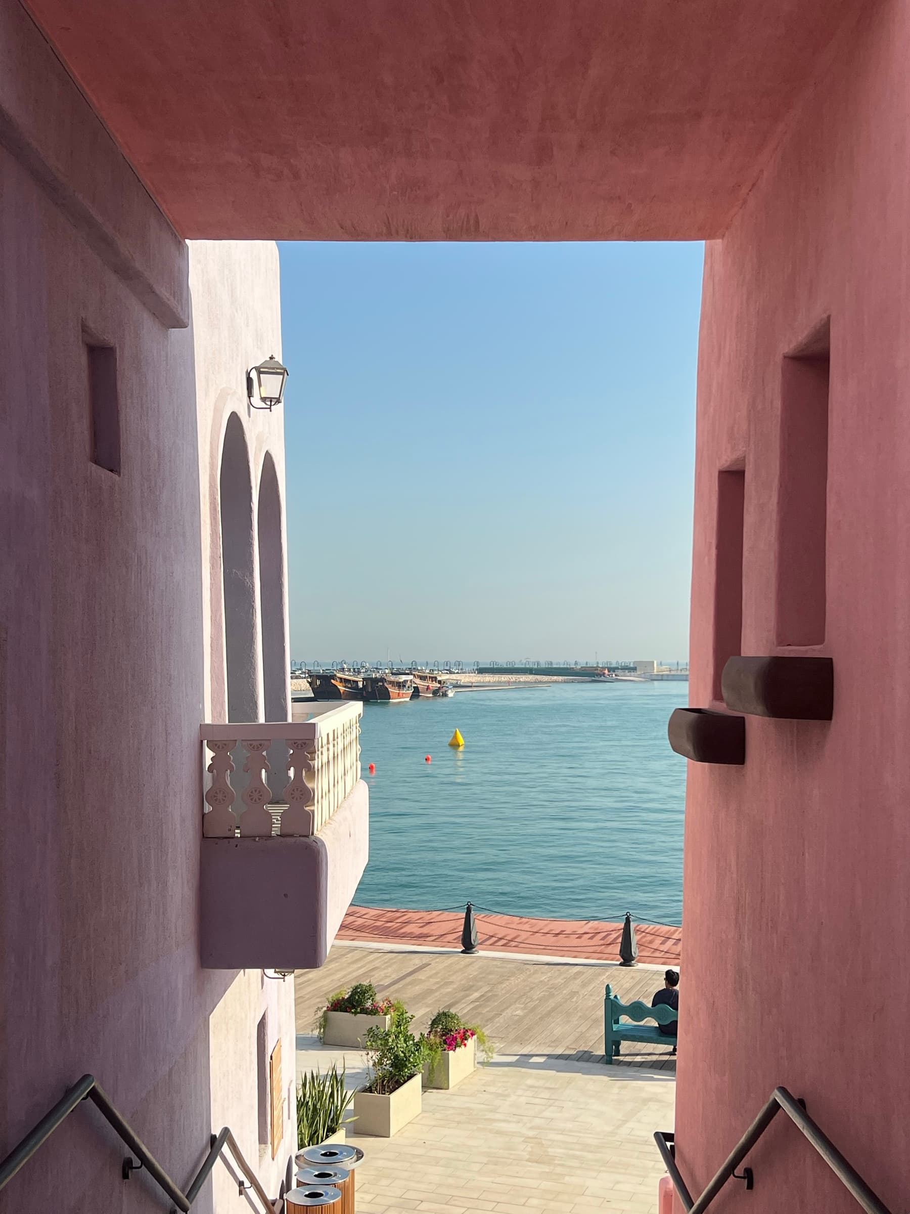 A pink-walled alley opening to the harbor in Doha